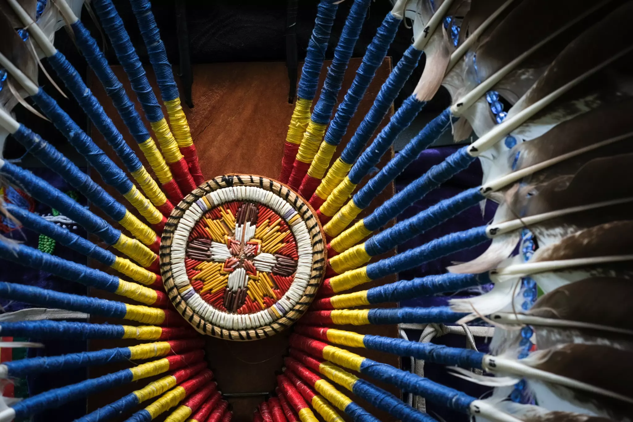 Close-up of Indigenous regalia made from feathers and multi-colored string.