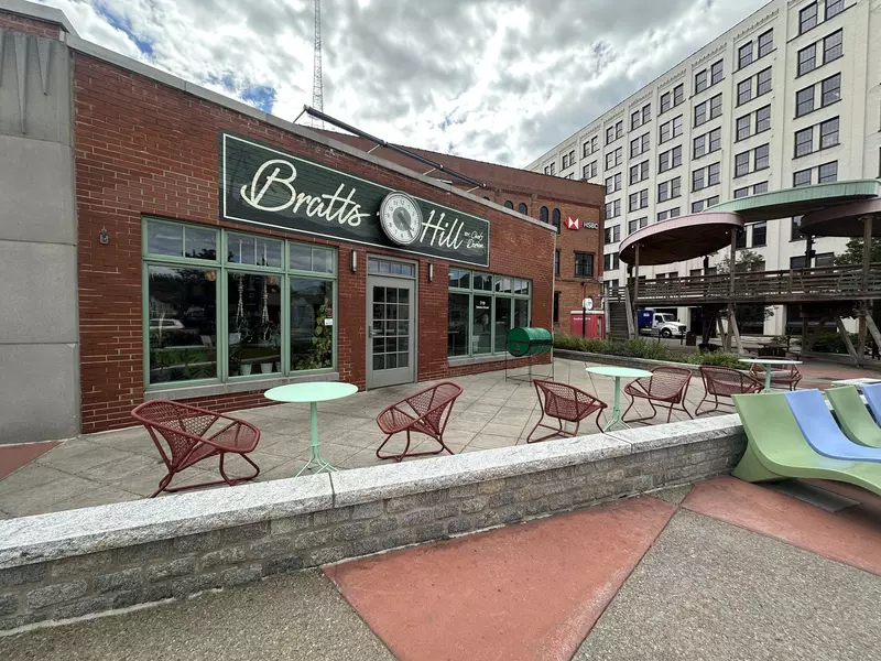 Brick building with a patio with colorful chairs. The sign says Bratts Hill. 