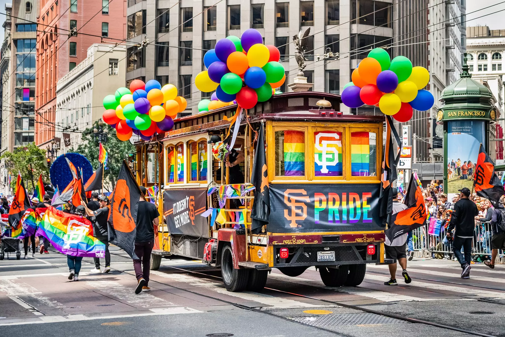 A former trolley car decorated in balloons of all colors and rainbow flags with "SF Pride" signs