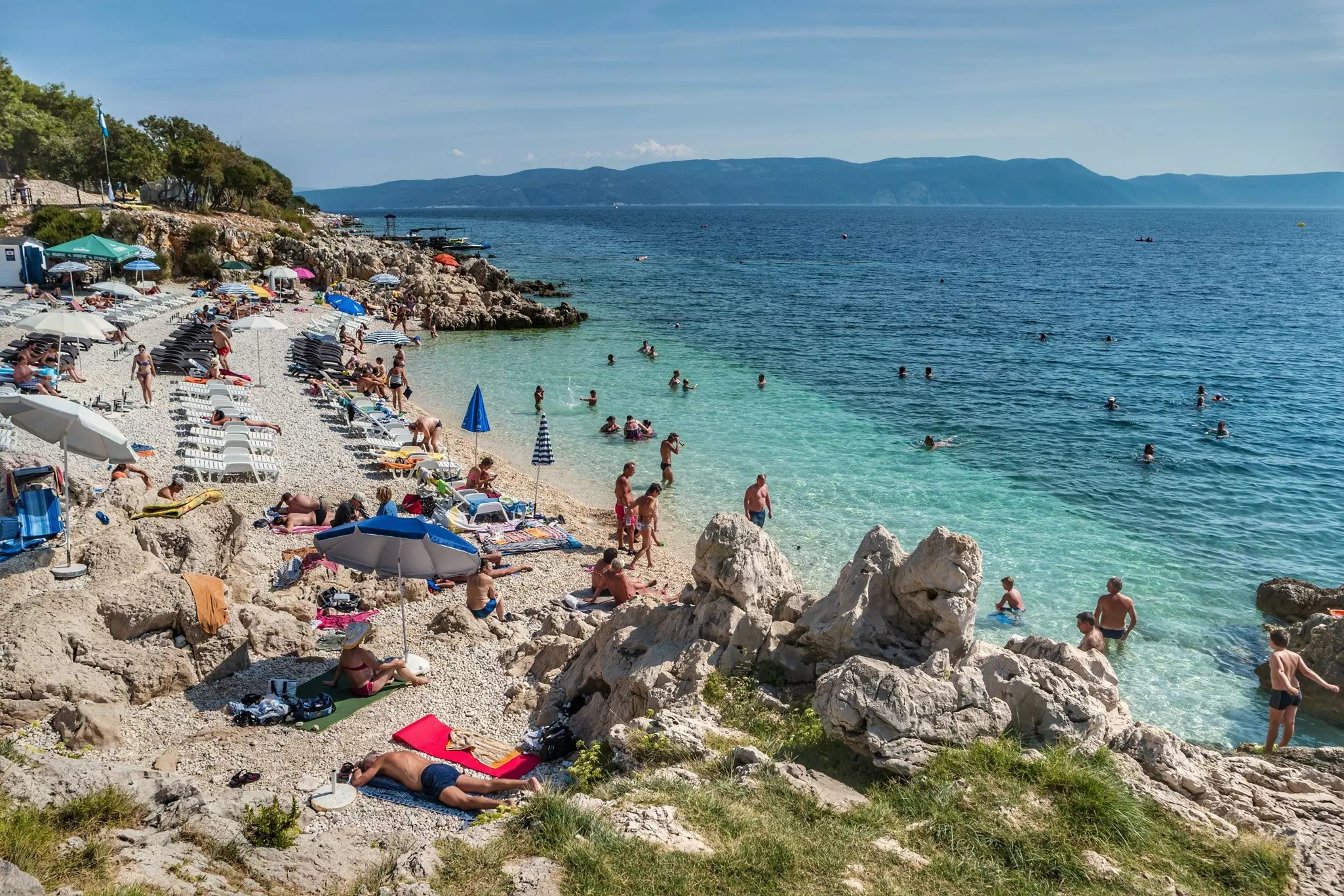People enjoying a pebble beach on the Adriatic ocean near Rabac, Istria, Croatia.