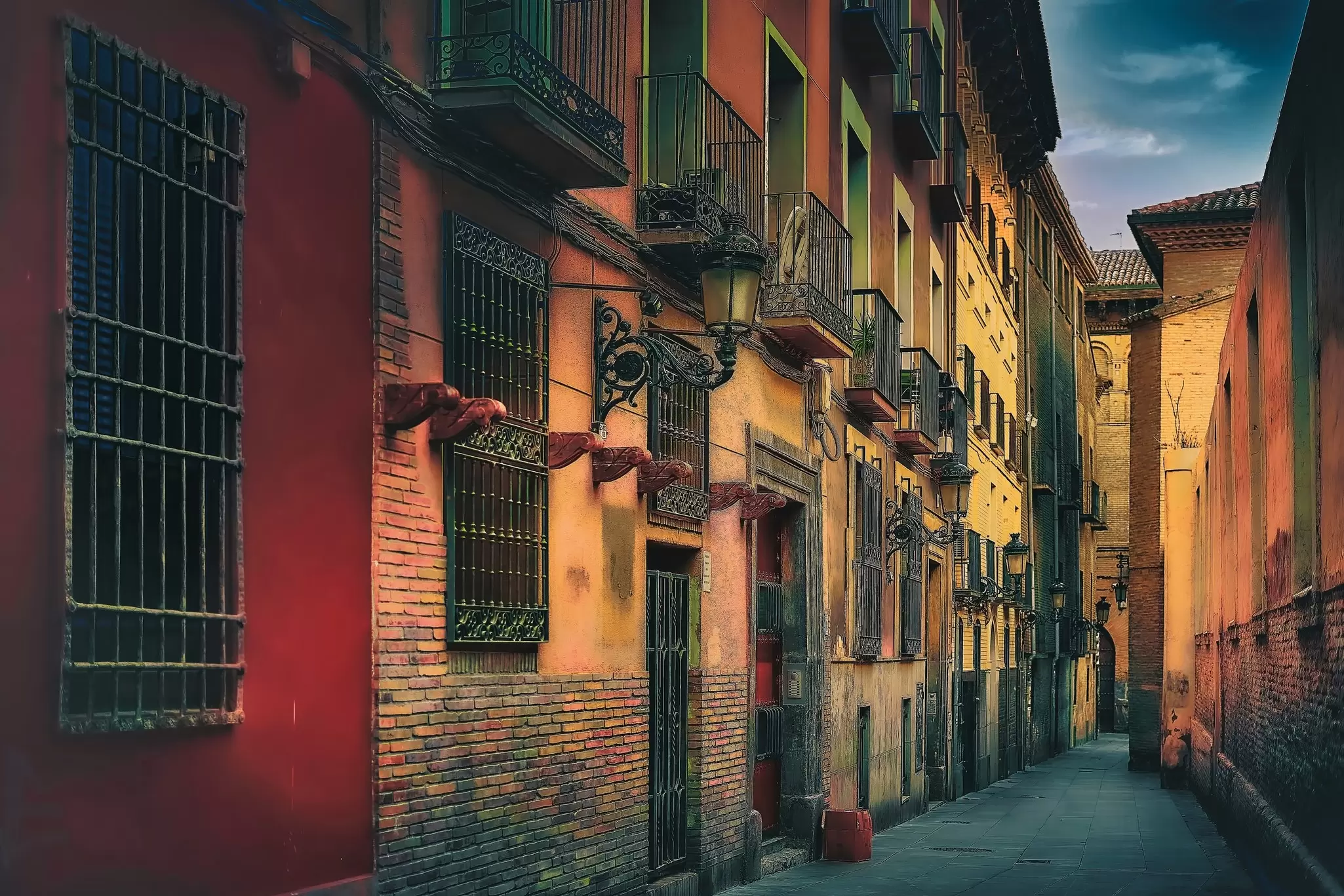 Houses with iron balconies line a lane in the old town of Zaragoza, Spain.