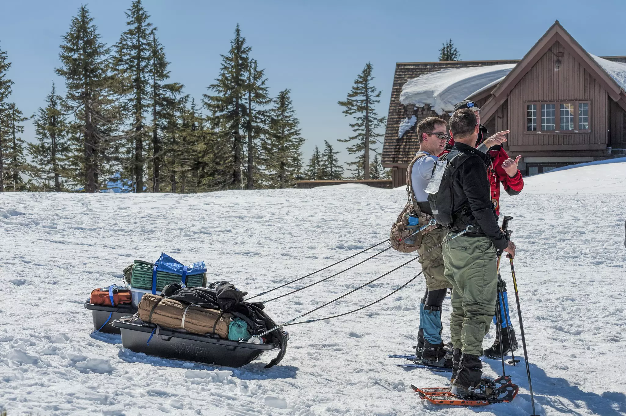 Snowshoeing hilkers get ready to head out for camping, pulling their gear behind in sleds