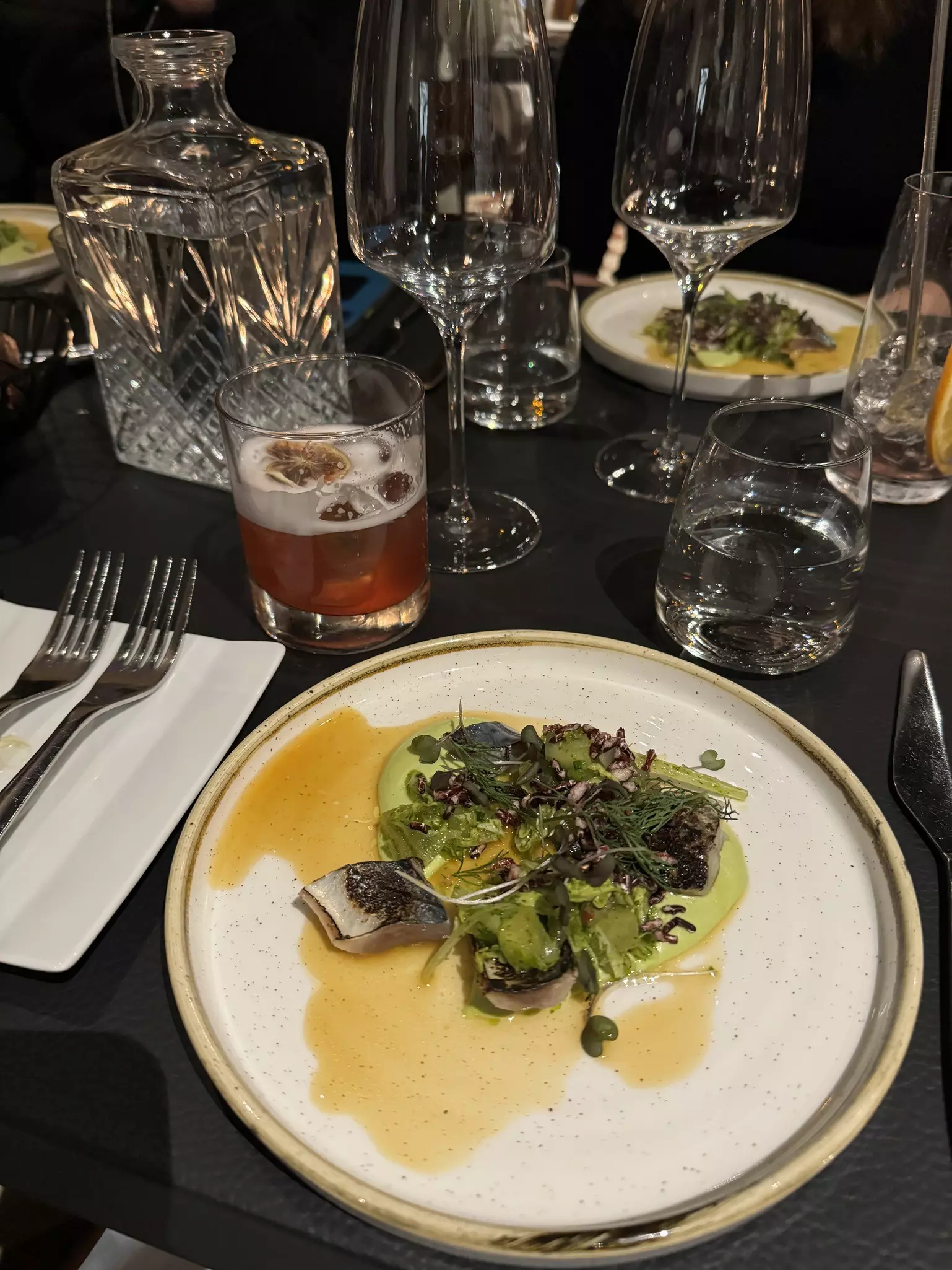 Cooked fish topped with salad, and a cocktail at Passio in Helsinki