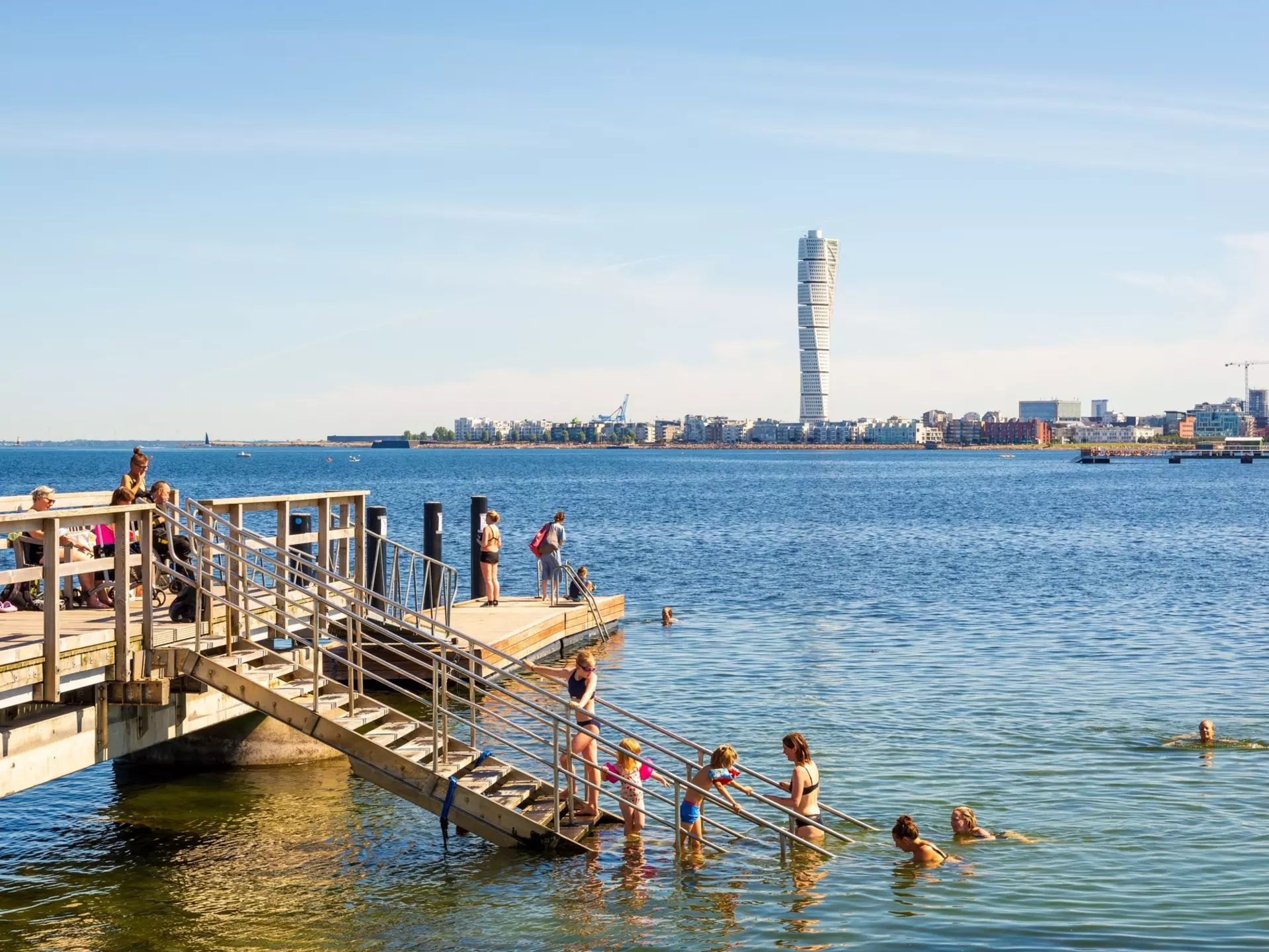 Families enjoying sea bathing on a sunny summer day on a pier at Ribersborg beach in Malmö.