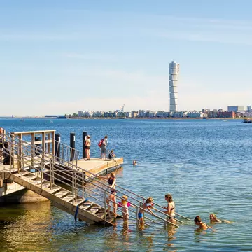 Families enjoying sea bathing on a sunny summer day on a pier at Ribersborg beach in Malmö.