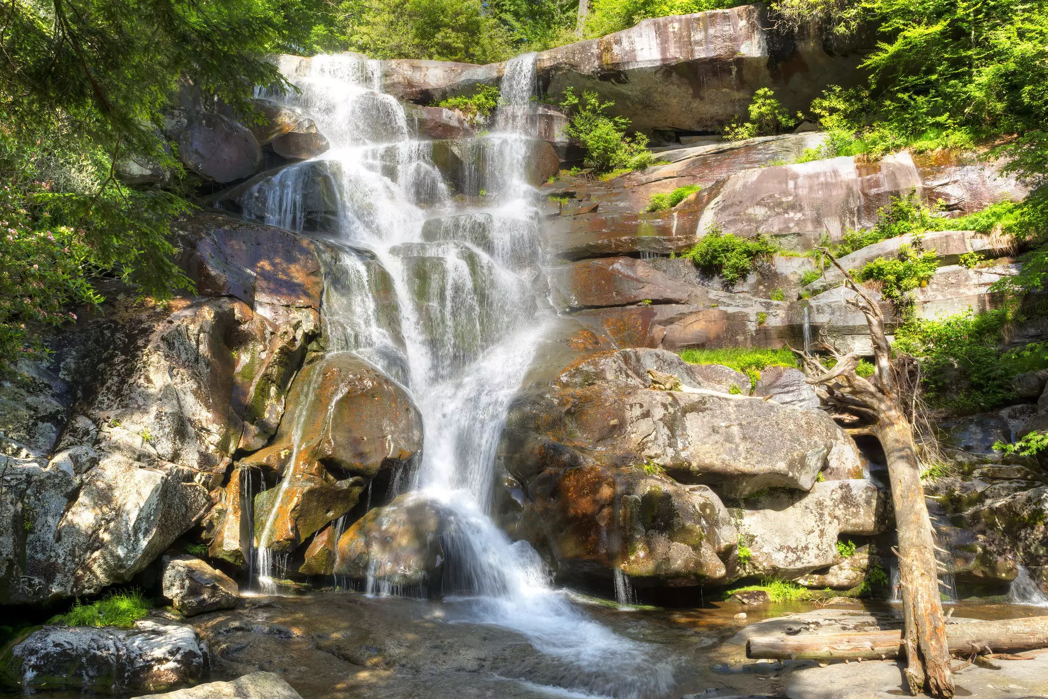 A waterfall cascades down a rock face into a shallow pool.