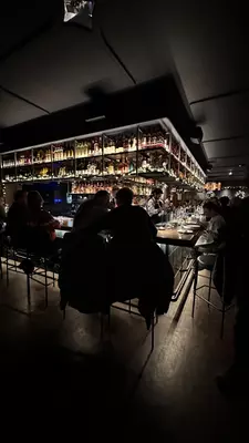 Two people in silhouette sit together at a well-lit bar