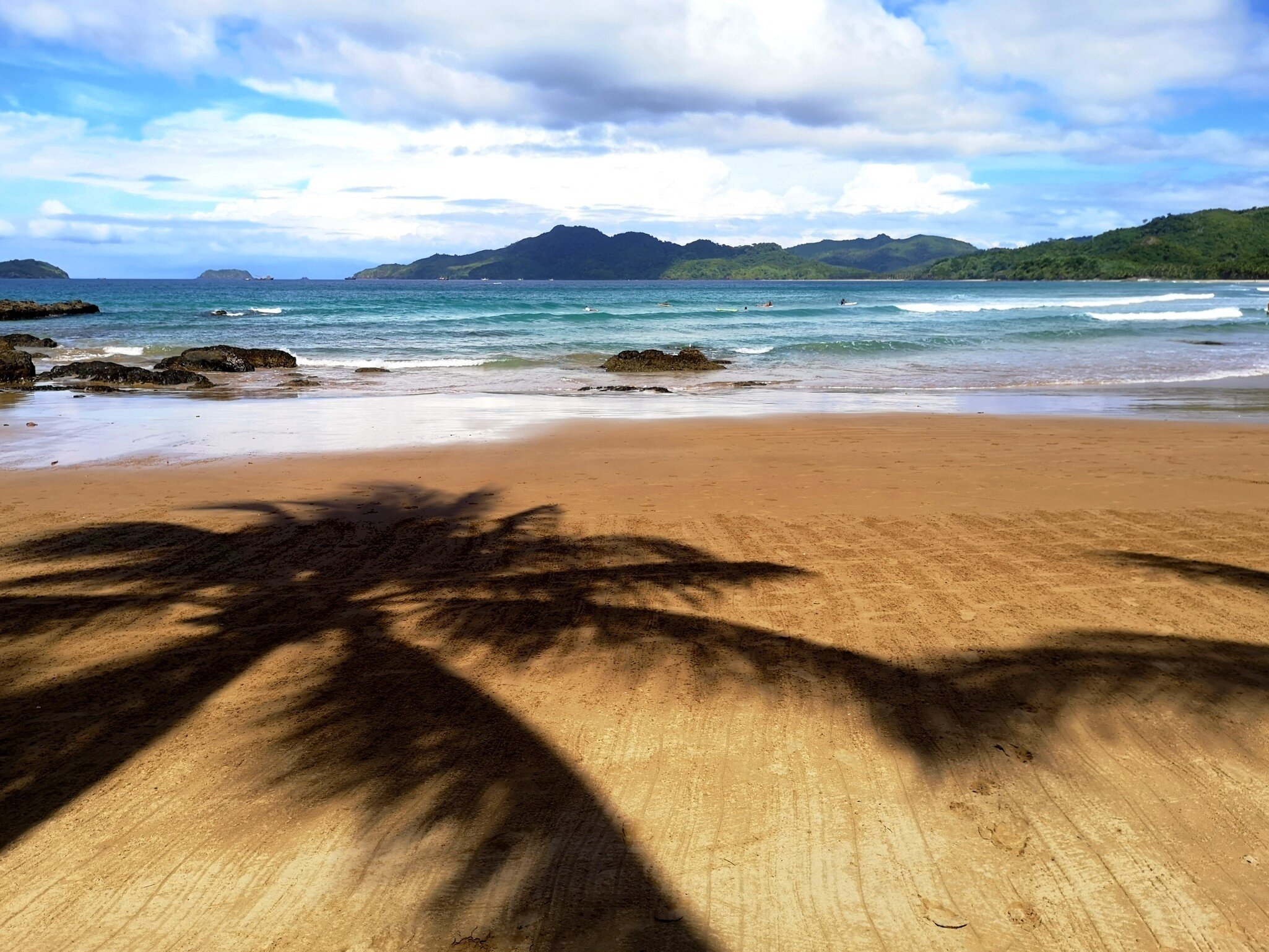 Shadows of palm trees on Duli beach, a surfing spot at El Nido.