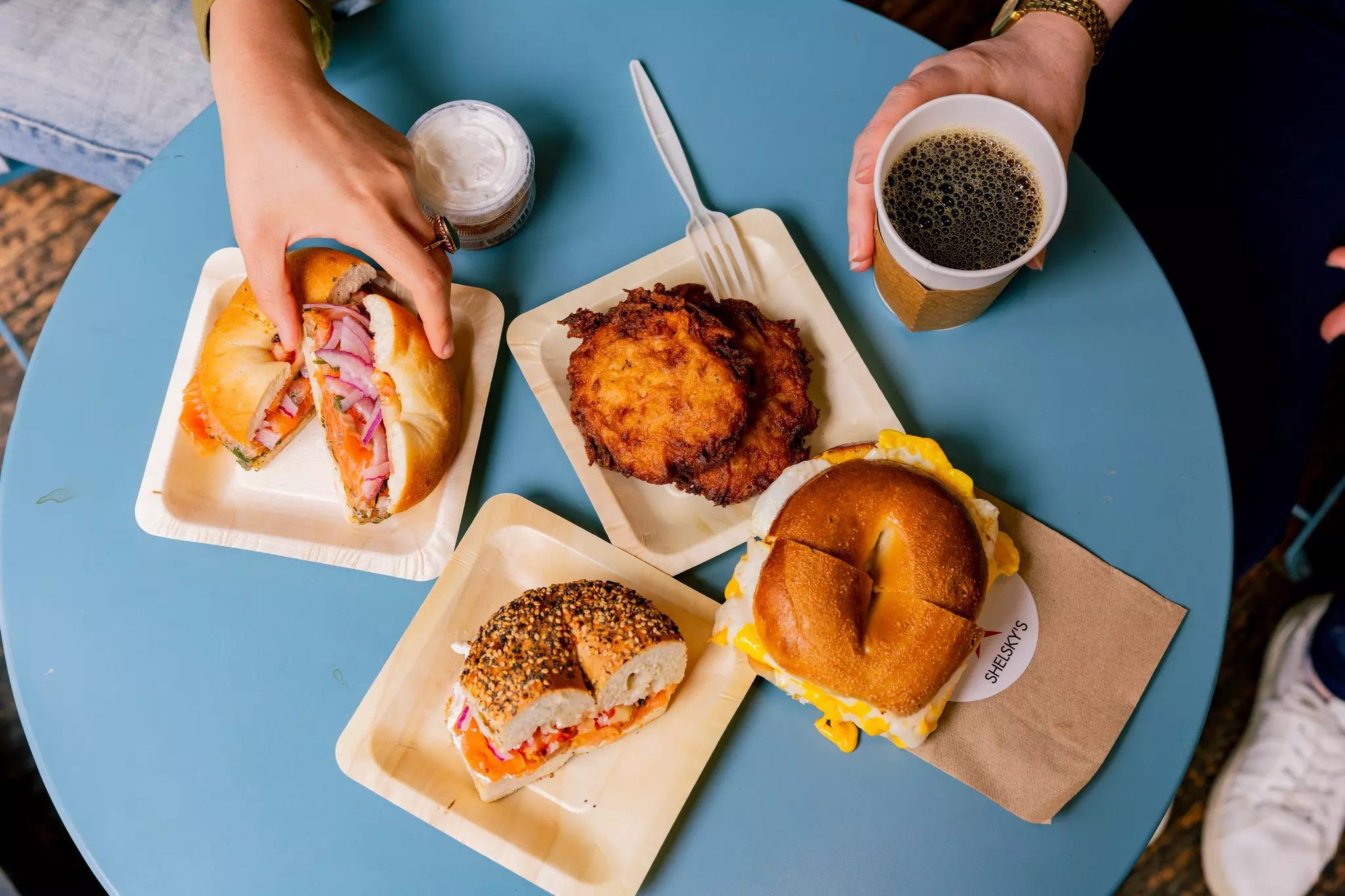 Top down view of a table with breakfast bagels and latkas. 