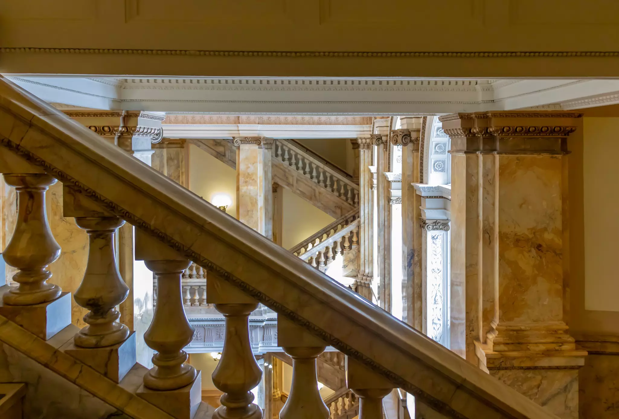 Elaborate marble steps with balusters are pictured in the interior of a public building.
