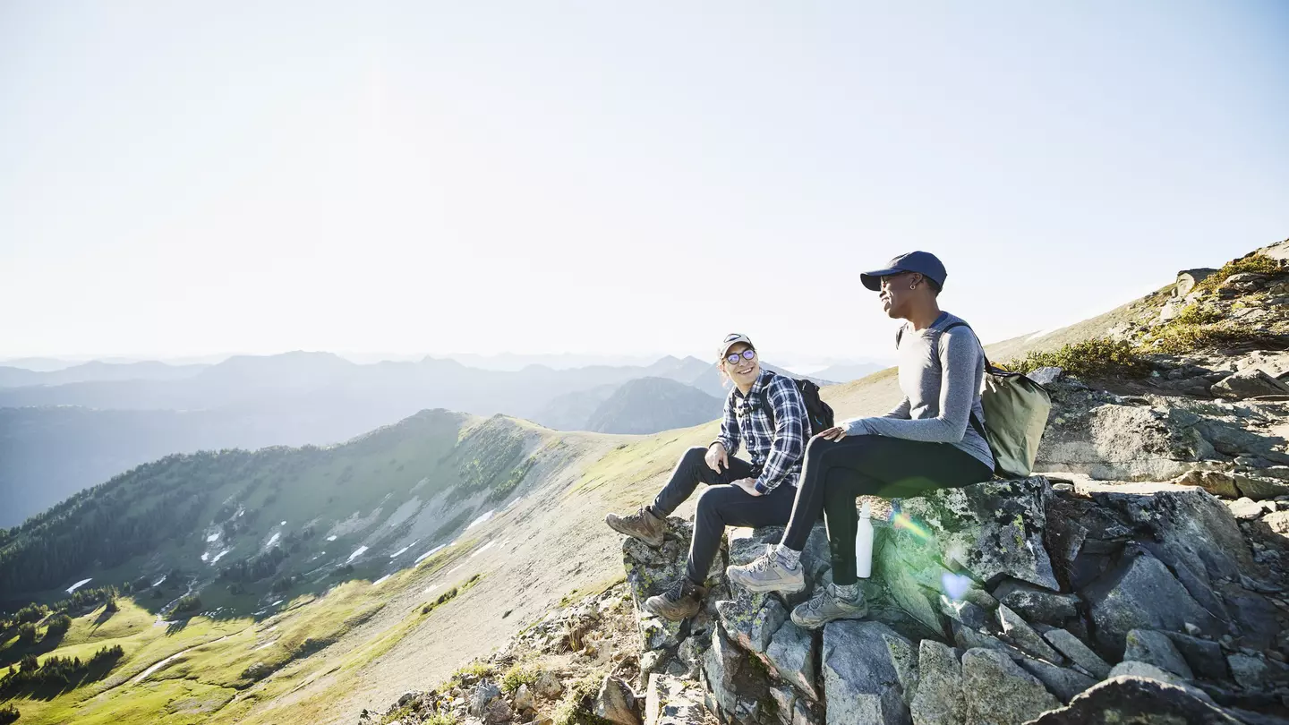 Smiling couple hanging out on rocks during early morning hike in mountains