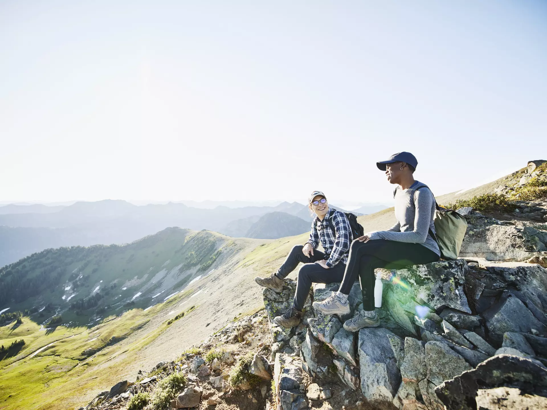 Smiling couple hanging out on rocks during early morning hike in mountains