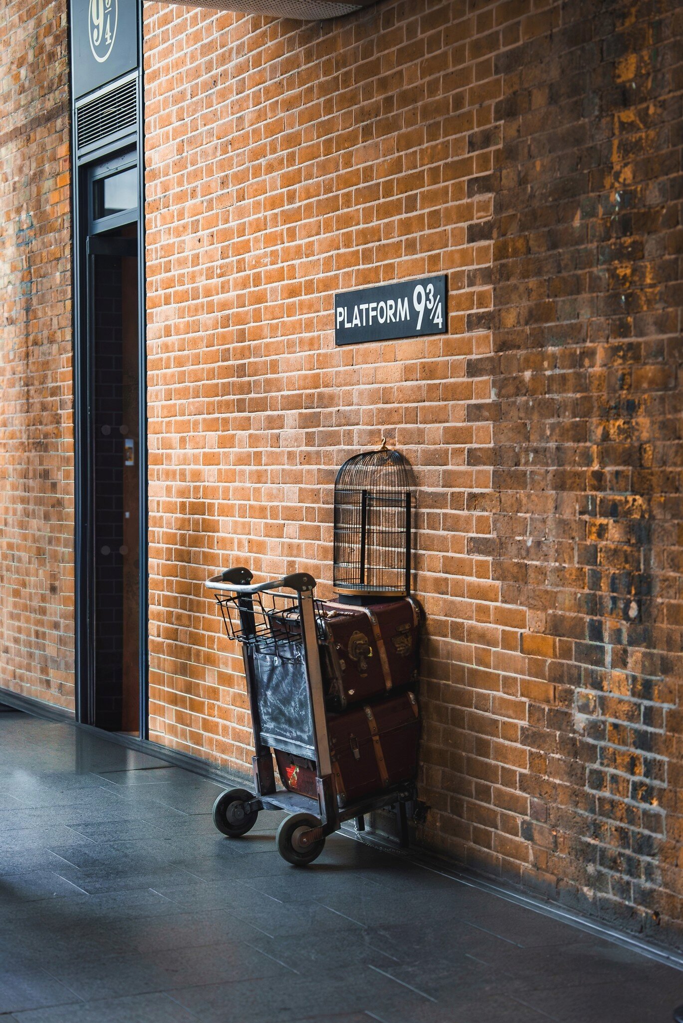 View of Platform 9¾ at King's Cross Station in London, UK, featuring a luggage trolley embedded in a brick wall, inspired by the Harry Potter series.
