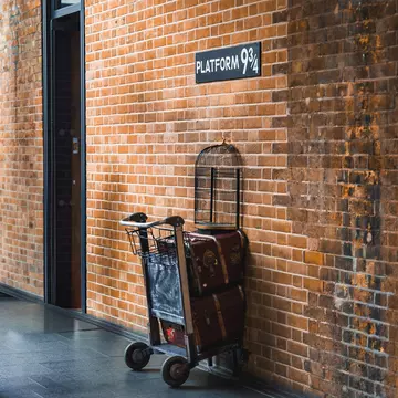 View of Platform 9¾ at King's Cross Station in London, UK, featuring a luggage trolley embedded in a brick wall, inspired by the Harry Potter series.