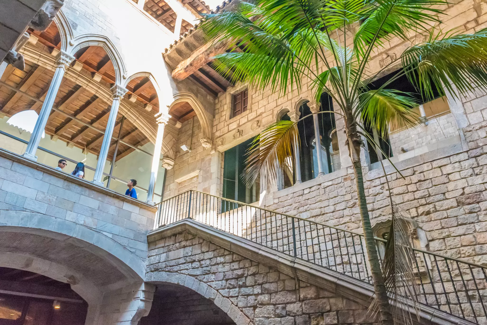 Stone courtyard with Gothic arched gallery, open staircase and palm tree at Museu Picasso, Barcelona