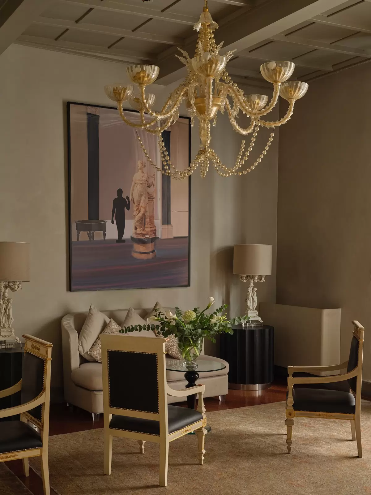 A cozy corner of a hotel lobby with armchairs, a couch and a gold chandelier
