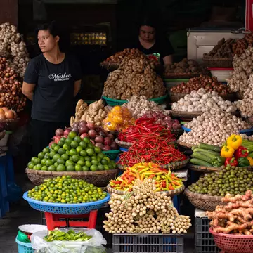 Two people standing by a display of produce and spices in baskets 