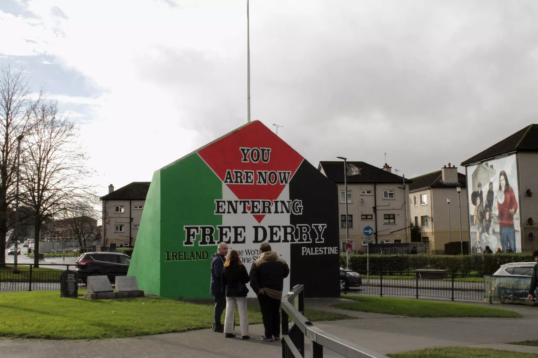 An installation painted in red, green, white and black that reads "You are now entering free Derry," with Ireland written on the green side and Palestine written on the black side.