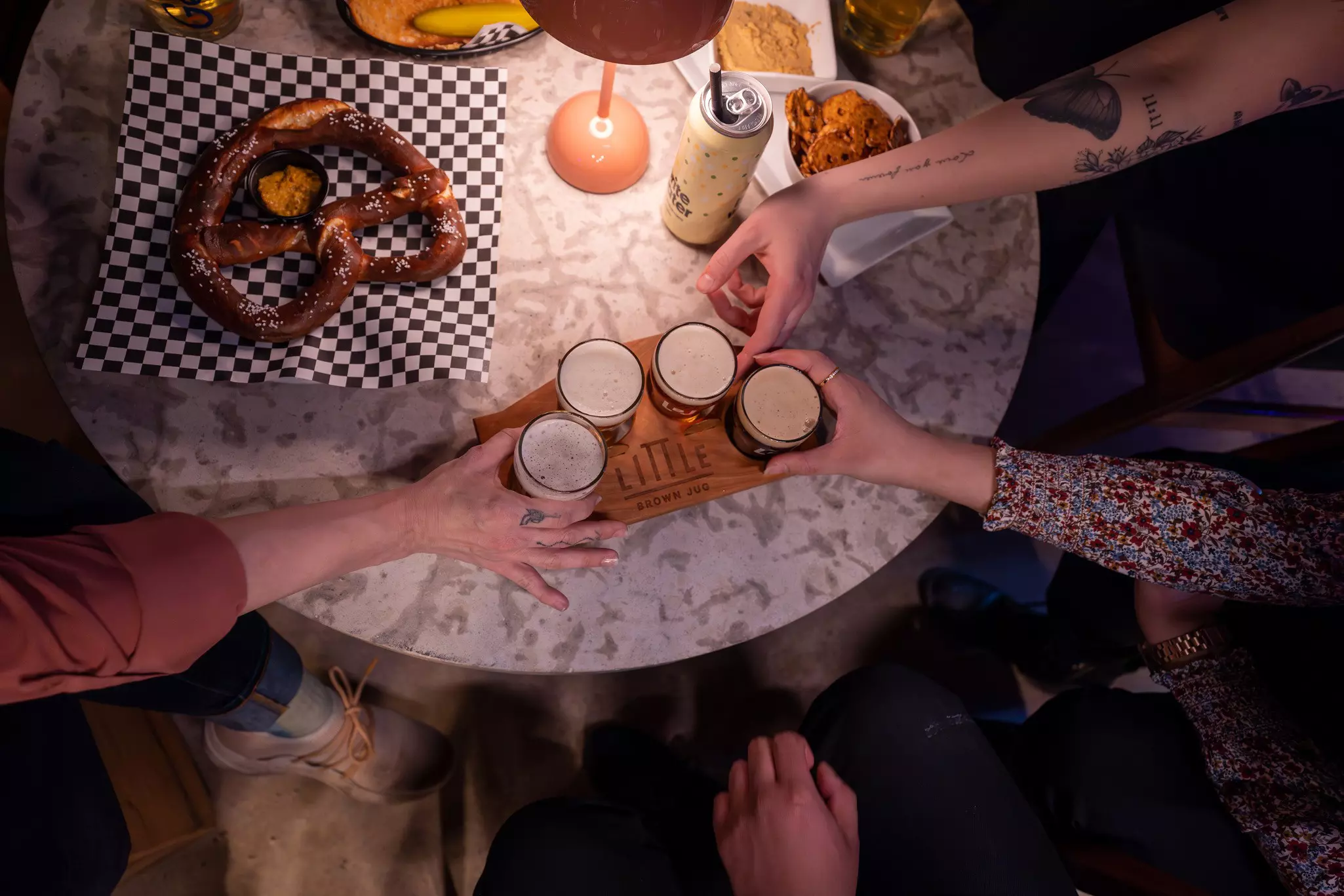 Hands reaching for a flight of beer at Little Brown Jug in Winnipeg, Manitoba