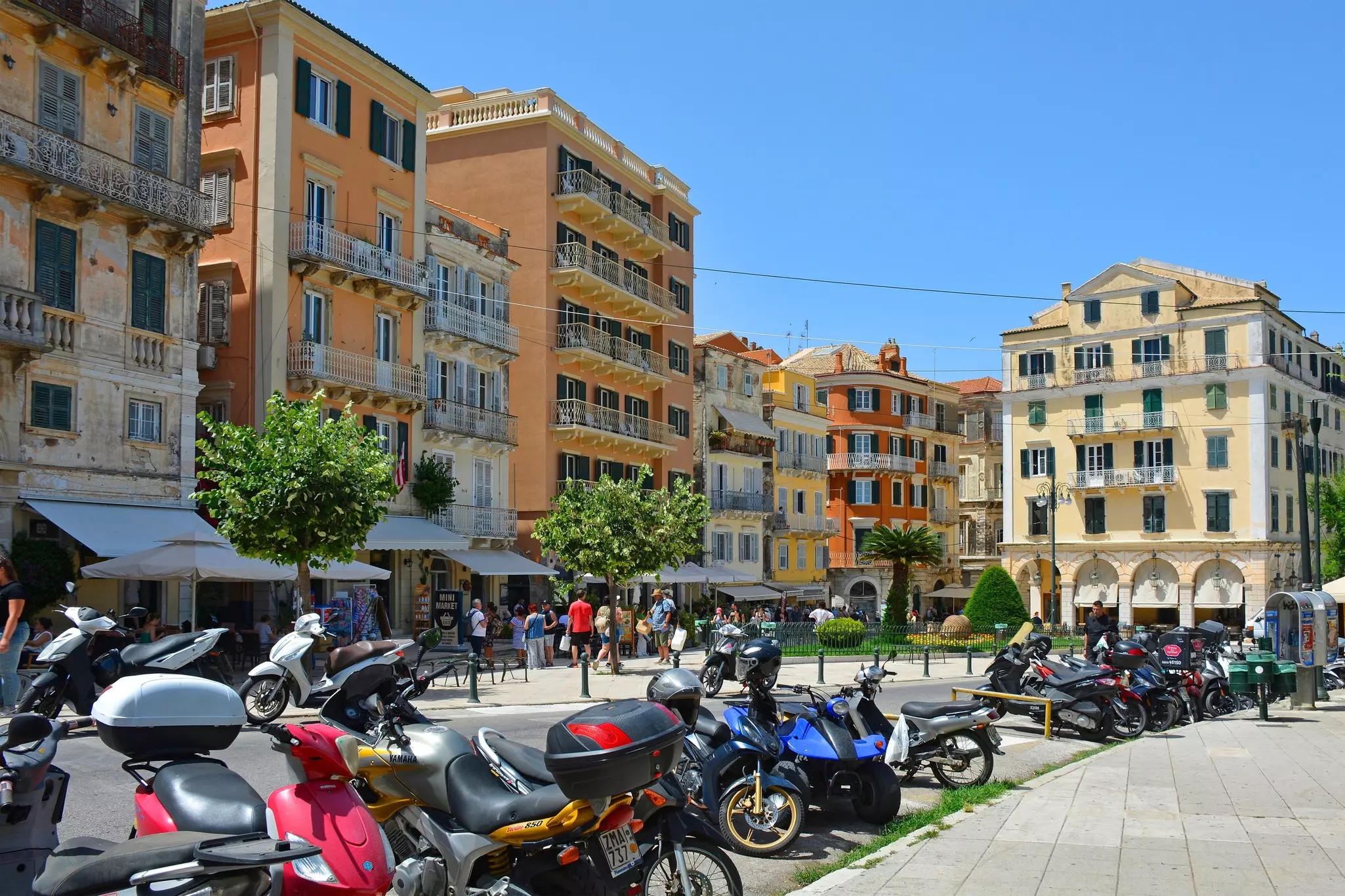 Scooters line the road at the junction between Eleftherias Street and Evgeniou Voulgareos Street in the historic centre of Corfu Old Town, Greece. A UNESCO World Heritage Site.