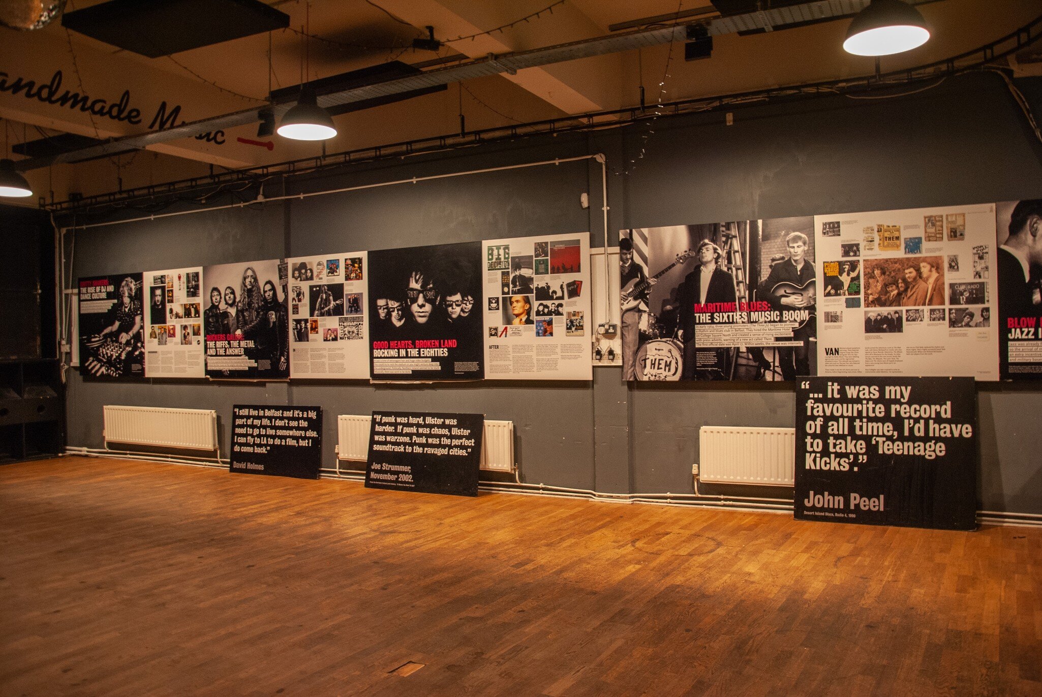 Dimly lit exhibition room dedicated to the famous musicians inside the Oh Yeah Music Center museum in Belfast, Northern Ireland. Wooden floor with posters on wall.