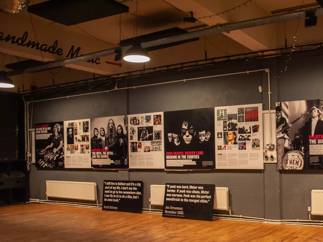 Dimly lit exhibition room dedicated to the famous musicians inside the Oh Yeah Music Center museum in Belfast, Northern Ireland. Wooden floor with posters on wall.