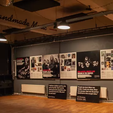 Dimly lit exhibition room dedicated to the famous musicians inside the Oh Yeah Music Center museum in Belfast, Northern Ireland. Wooden floor with posters on wall.
