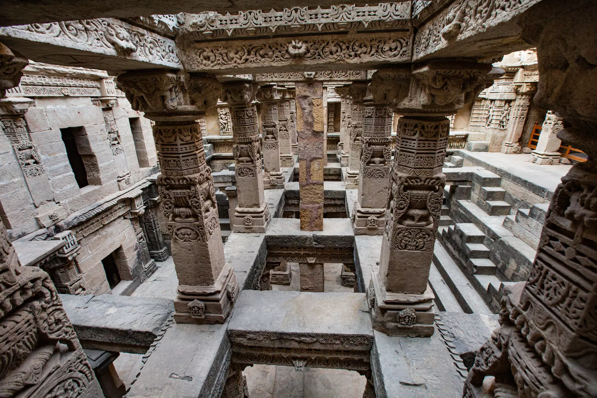 Multiple levels of carved columns and stairs are pictured in a man-made underground cavern.