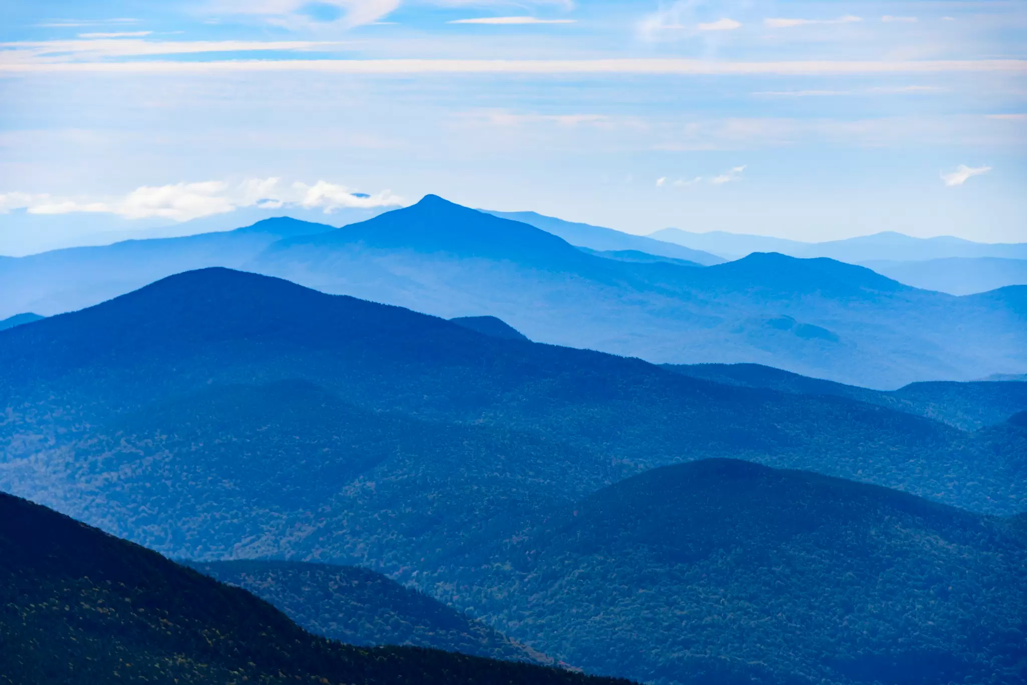 A mountain range in shades of green and blue