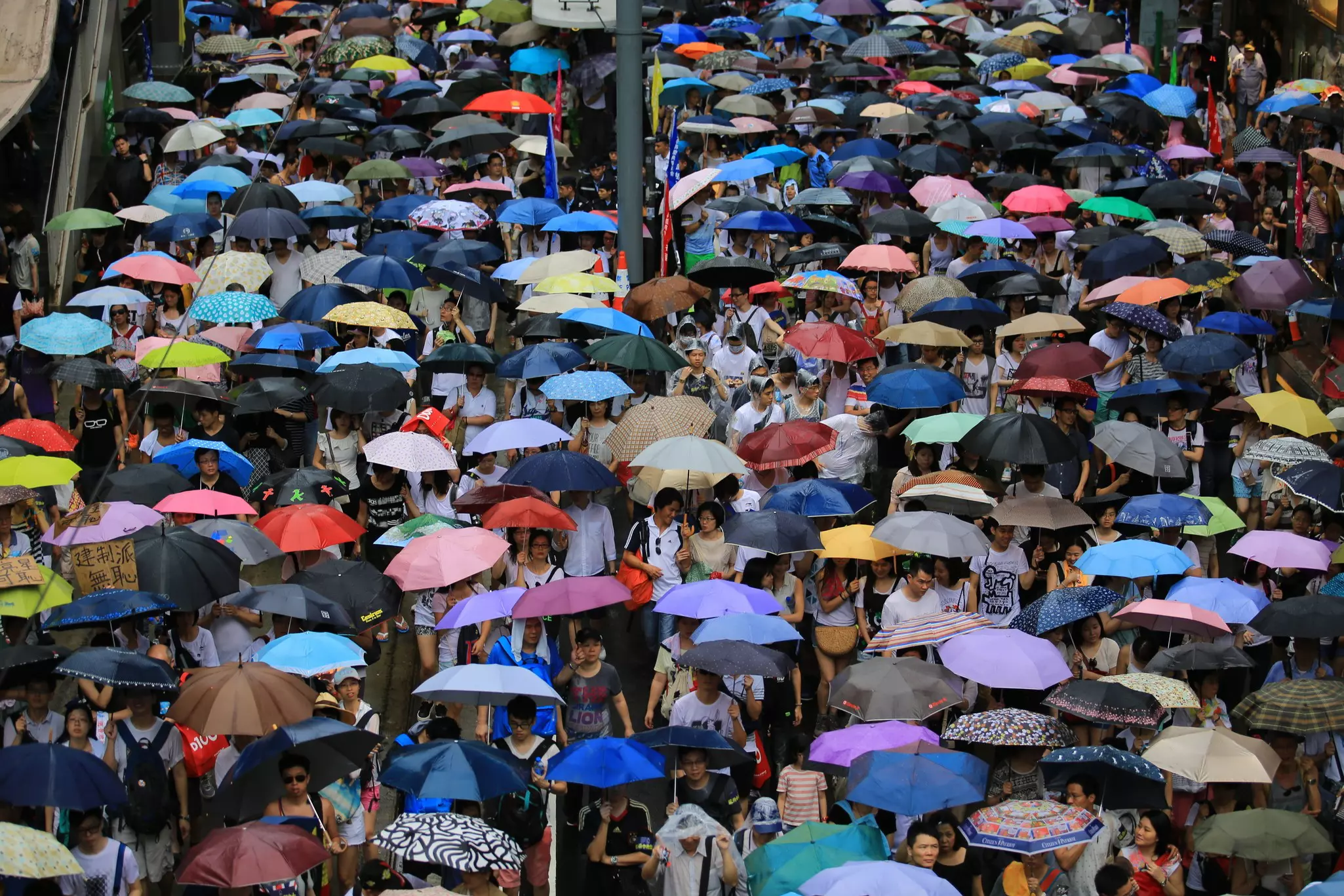 Hong Kong citizens in the street with umbrellas on a rainy day.