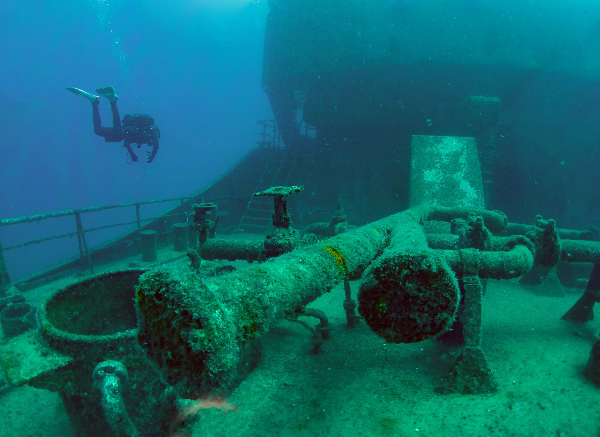 A scuba diver swims near the wreck of a tanker