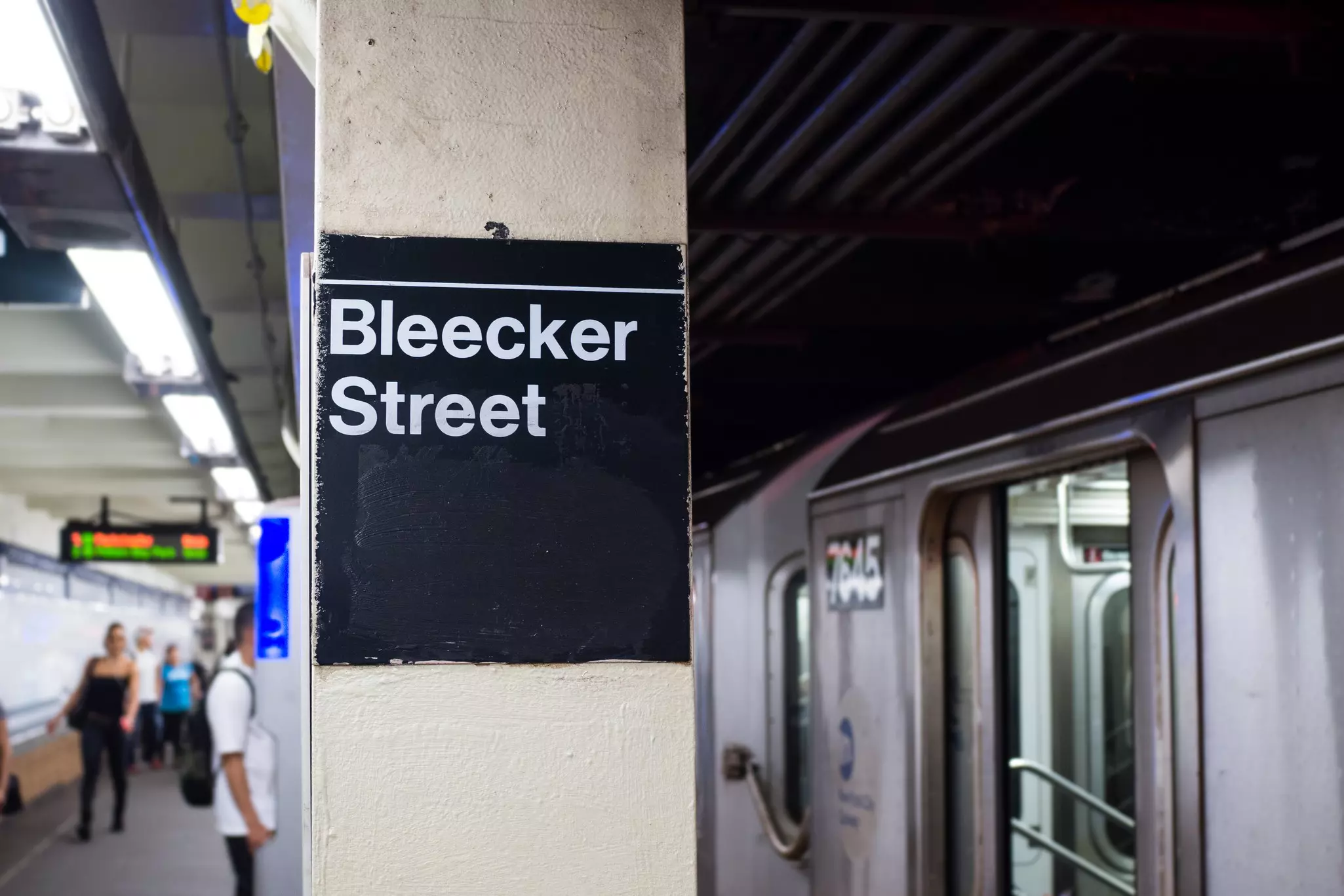 Sign inside Bleecker Street station ,New York with train at platform