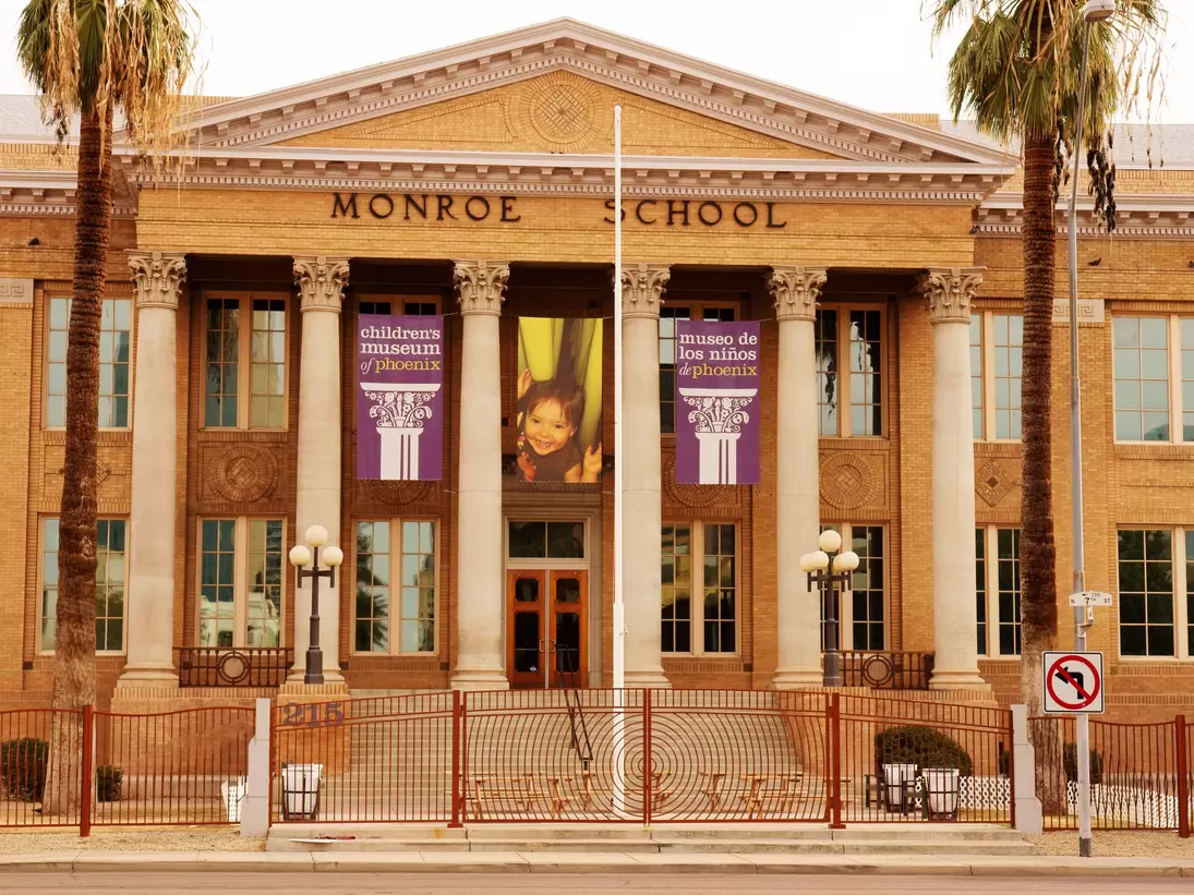 Columned brick facade of the historic Monroe School with Children's Museum of Phoenix banners