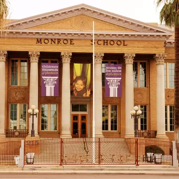 Columned brick facade of the historic Monroe School with Children's Museum of Phoenix banners