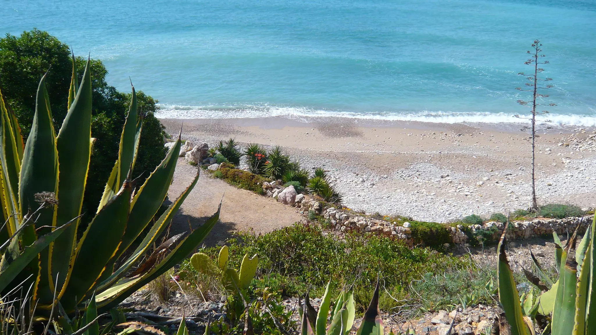 A steep cliff bath leads down to a secluded sand and pebble beach.