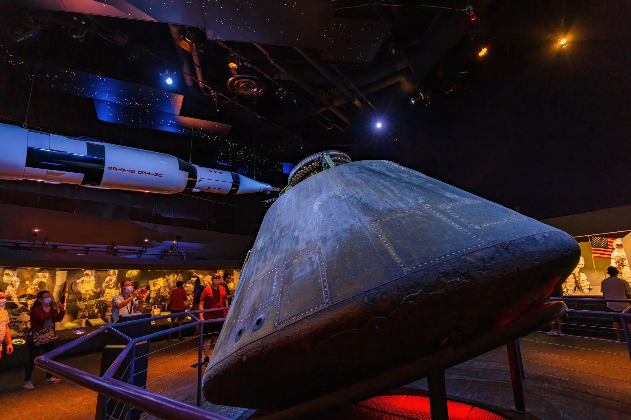 A space capsule and rocket are on display in a huge gallery related to space travel.