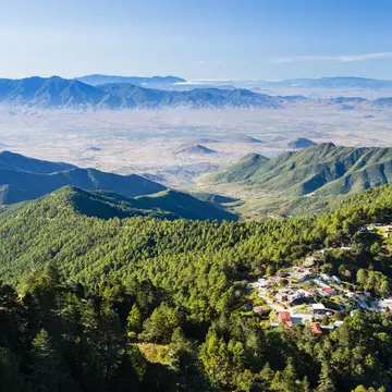 Forested mountains with a small village and a distant hazy valley.