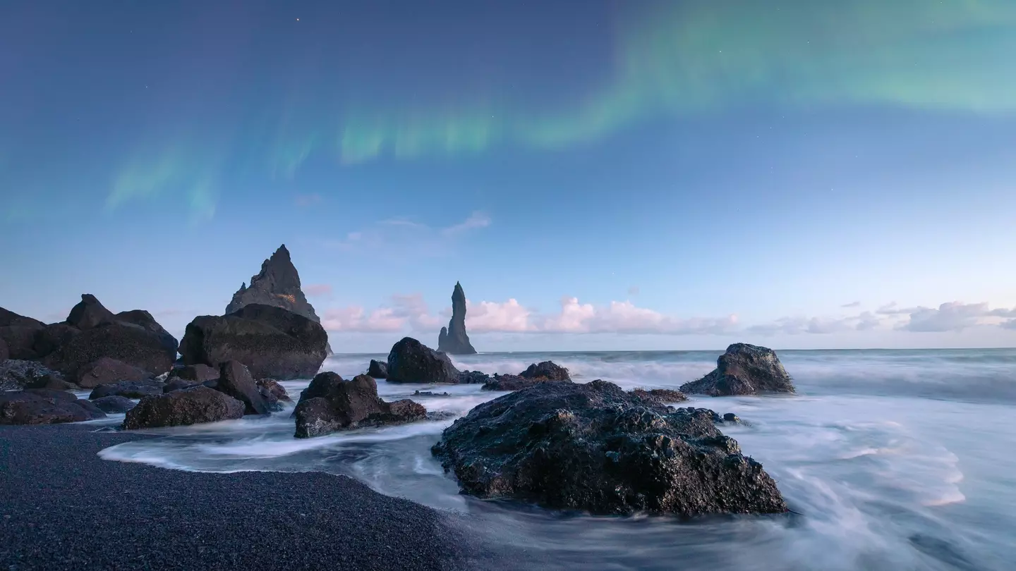 The black sand beaches of Iceland with the northern lights above.