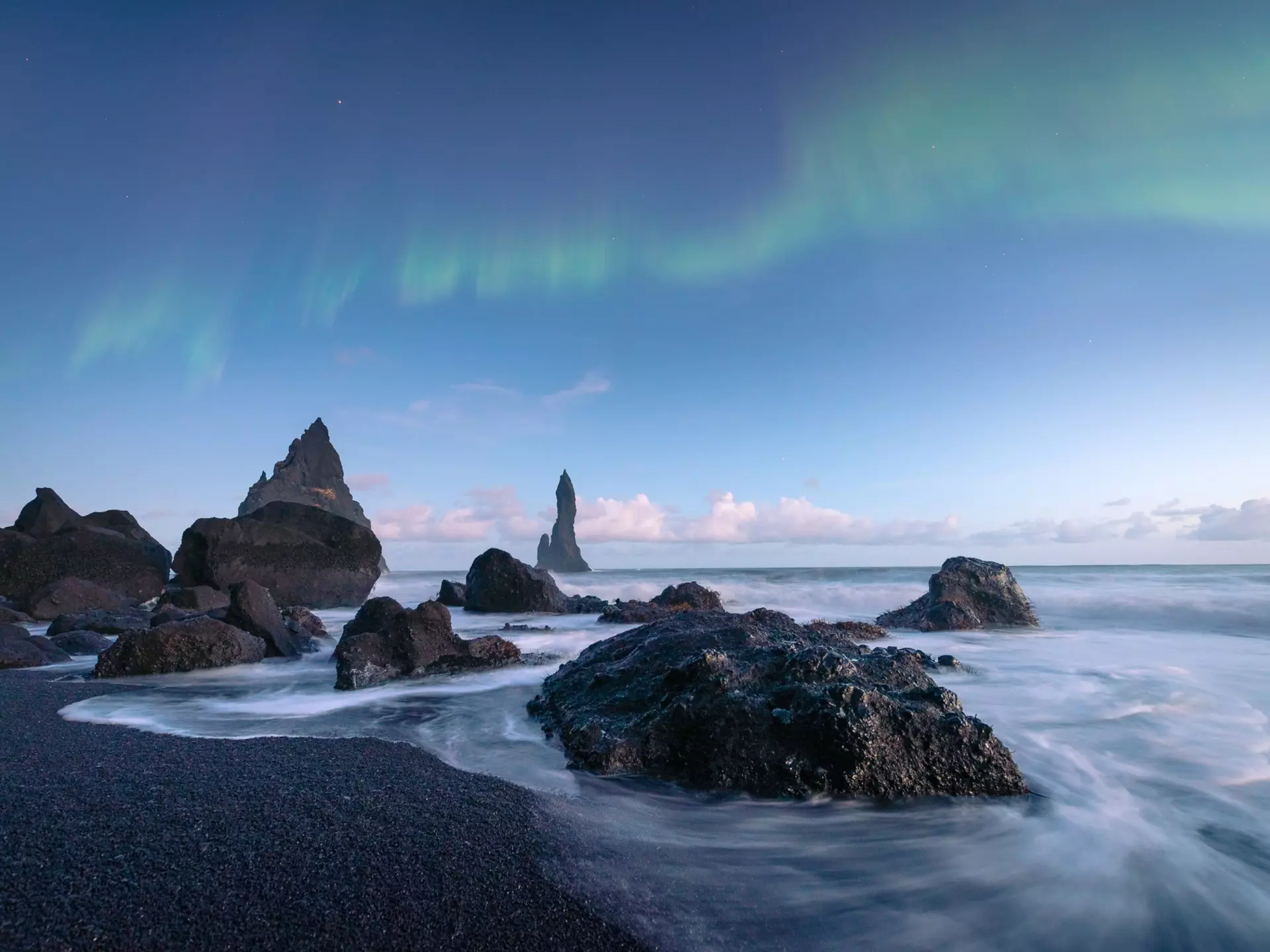 The black sand beaches of Iceland with the northern lights above.