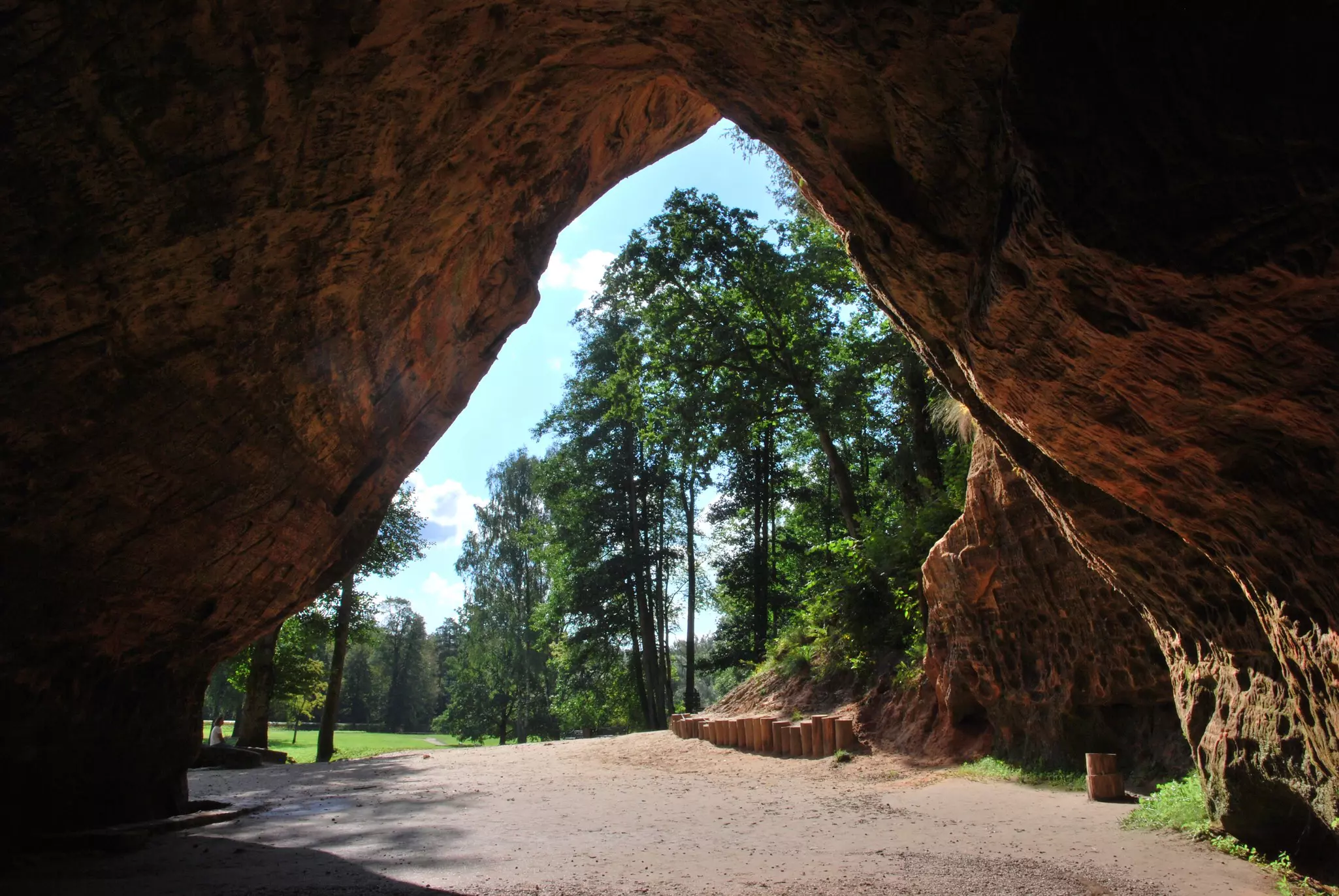 Looking out from a rock cave at trees on a sunny day.