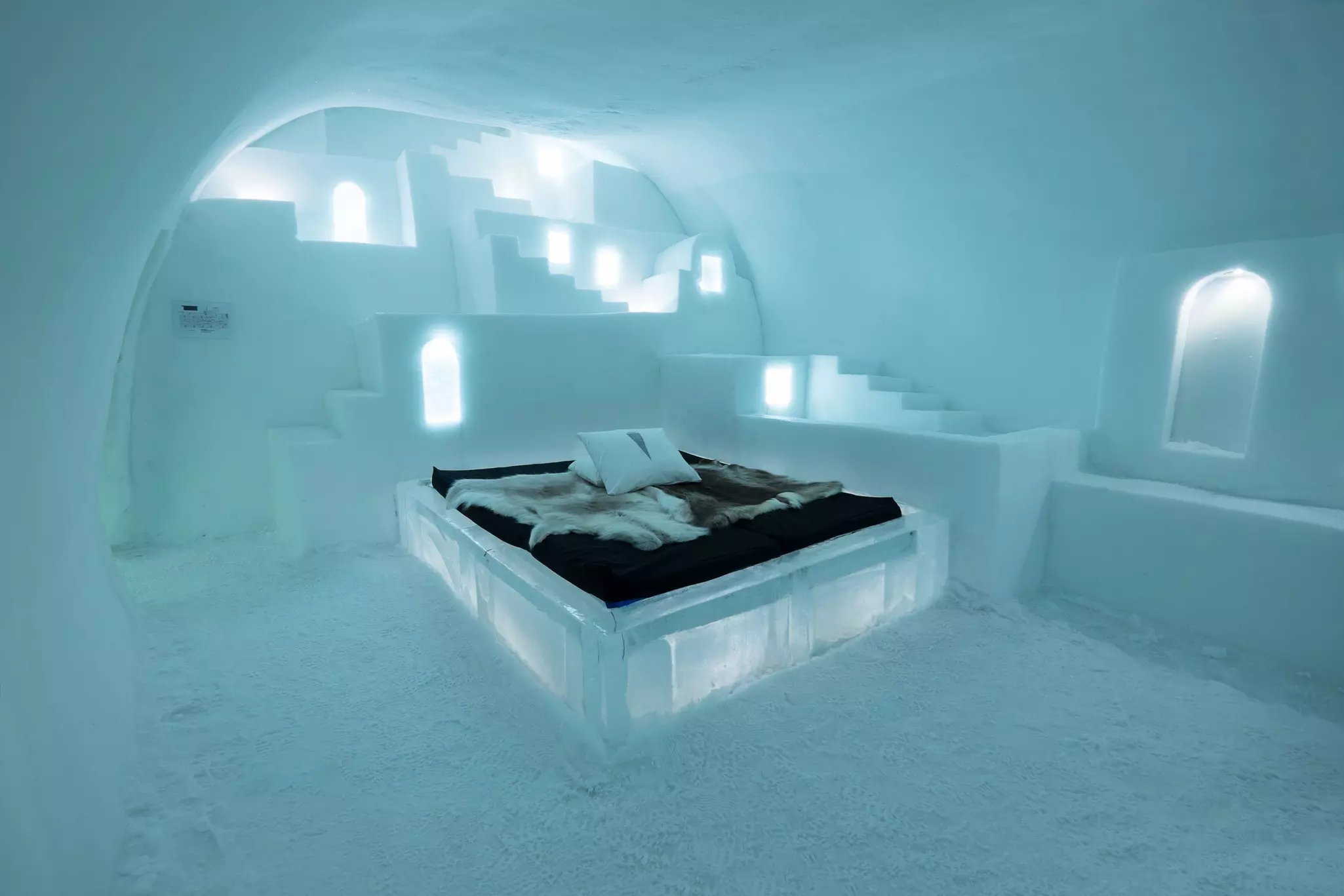 In a room sculpted from ice, an ice bed is covered with animal hides.