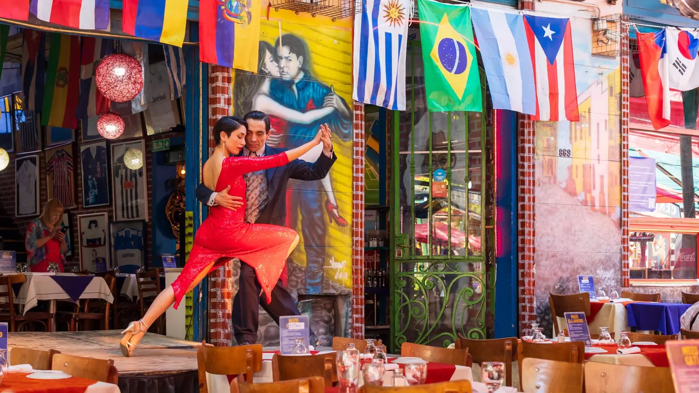 Two people tango on stage at a restaurant in Caminito