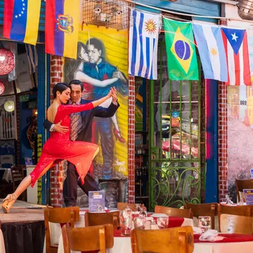 Two people tango on stage at a restaurant in Caminito