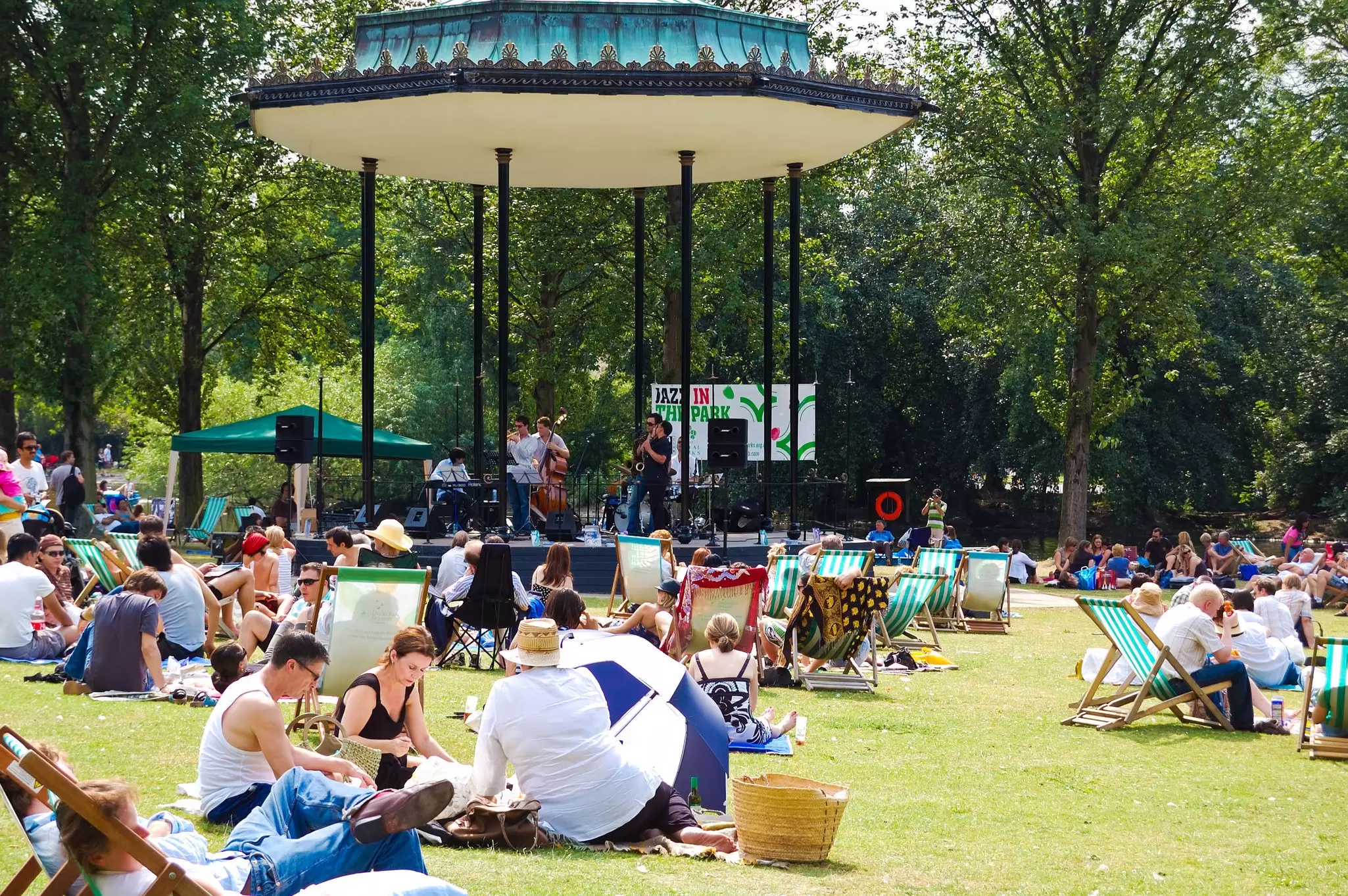 People enjoying a concert by the bandstand during summer in Regent's Park, London, UK.