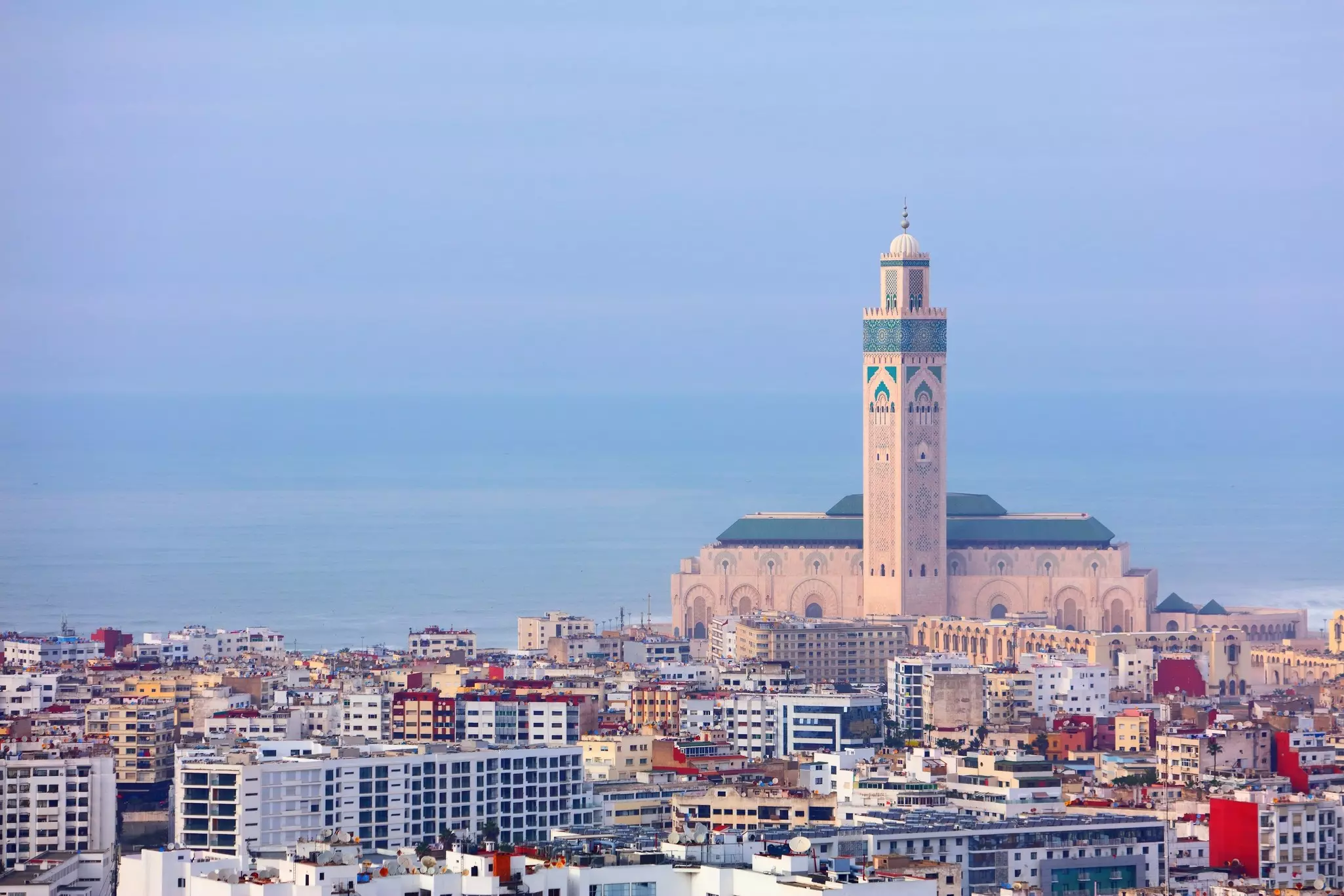 A wide view of a dense city by the water, with a large mosque.