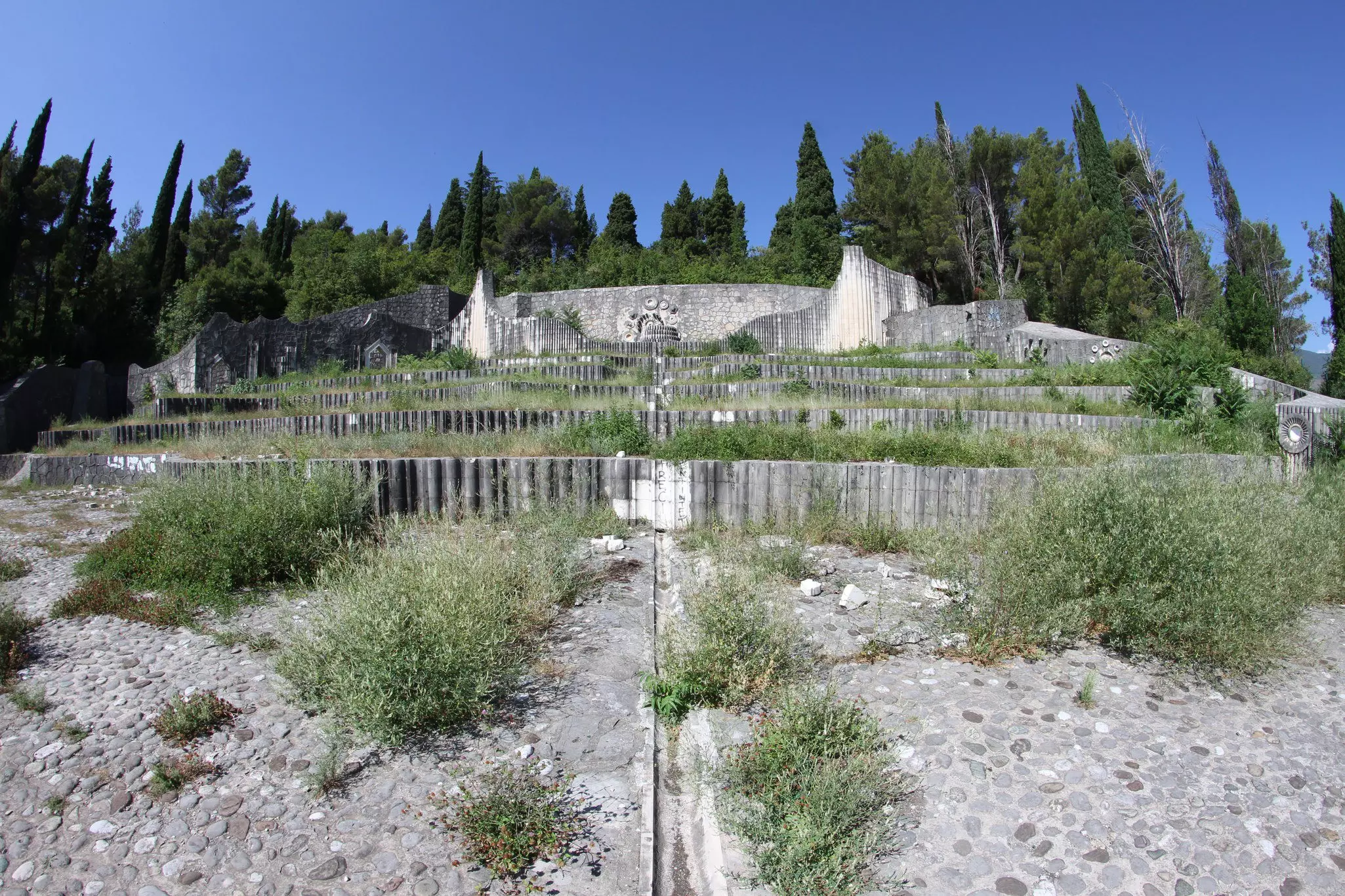 Gray walls in an overgrown cemetery.
