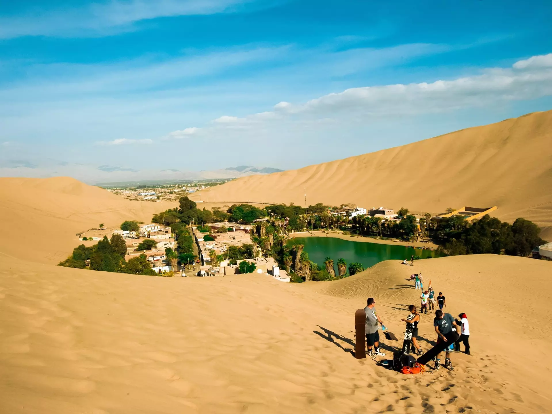 Tourists sand board in the dunes of Ica Peru.