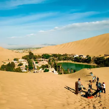 Tourists sand board in the dunes of Ica Peru.