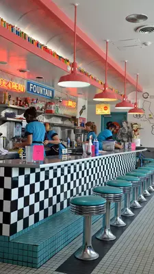 Servers work behind the counter of a brightly decorated diner.