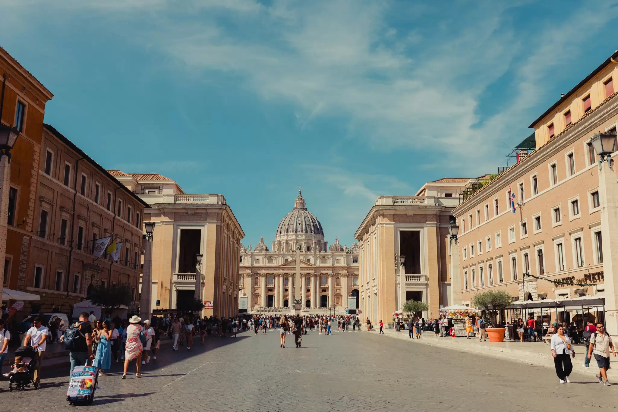 A church with a large dome at the end of a wide pedestrian street.